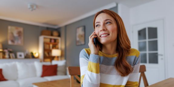 Frau sitzt an einem Tisch und telefoniert