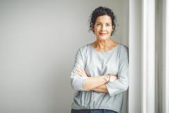 Frau lehnt lächelnd an einer Wand