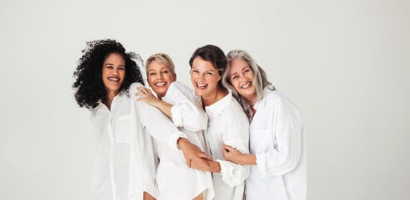 eine Gruppe von Frauen in weißen Oberteilen lachen zusammen